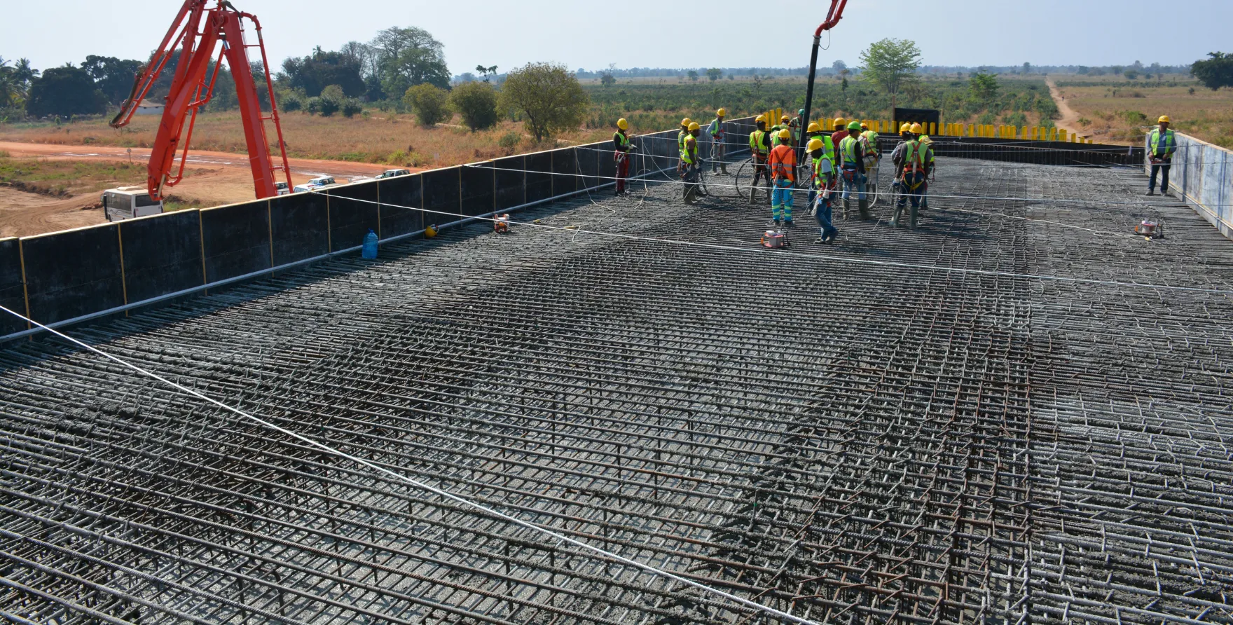 Crew working with boom pump to place concrete across reinforced structural slab during construction