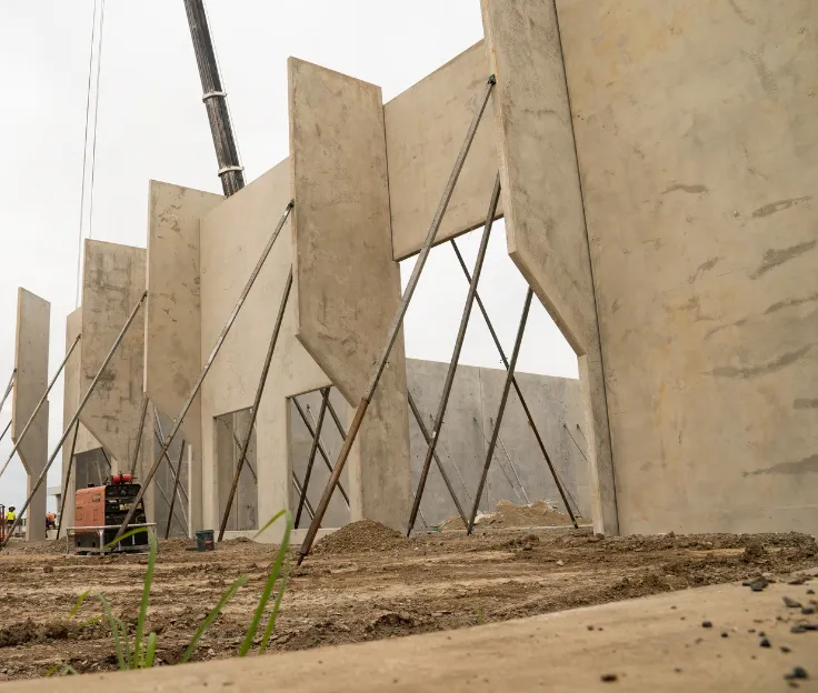 Tilt-up concrete wall panels being braced and secured on commercial job site