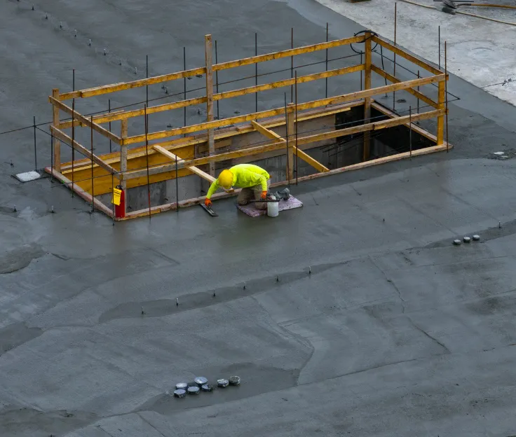 Worker smoothing wet concrete during a structural slab installation in Los Angeles